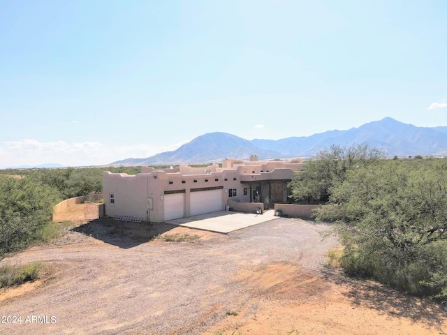 view of front of home with dirt driveway, an attached garage, and a mountain view