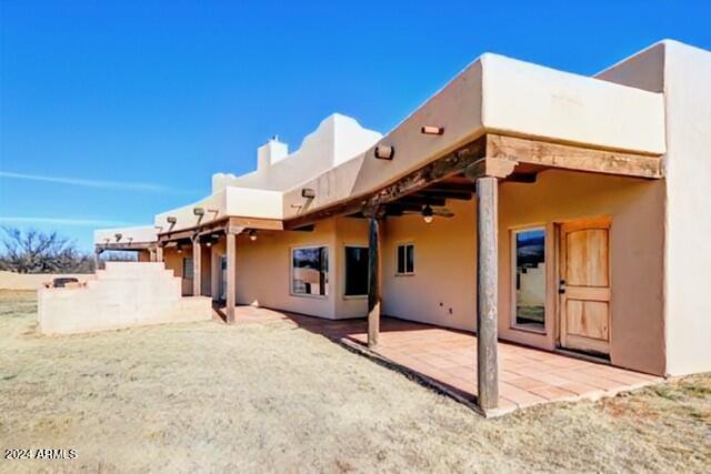 back of house with stucco siding, ceiling fan, and a patio