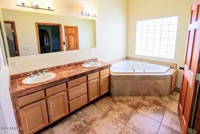 bathroom with vanity and tiled tub