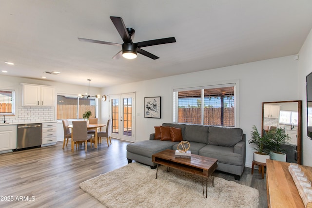living area with light wood-style flooring, a chandelier, ceiling fan, and recessed lighting