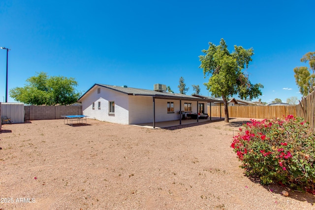 back of house featuring a trampoline, a patio, a fenced backyard, cooling unit, and a shed
