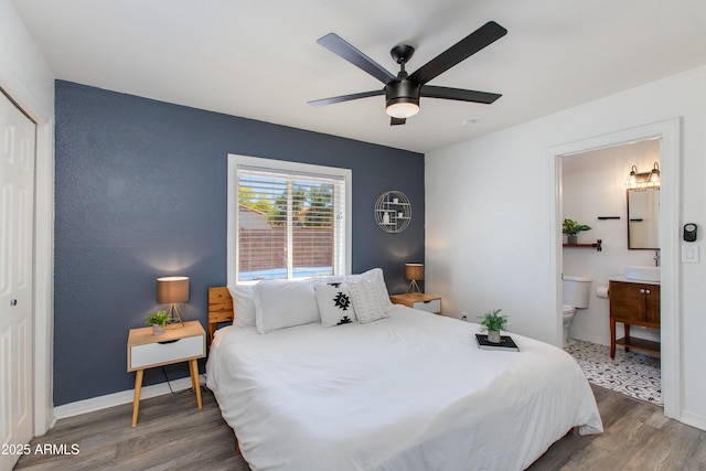 bedroom with wood finished floors, a closet, connected bathroom, ceiling fan, and a sink