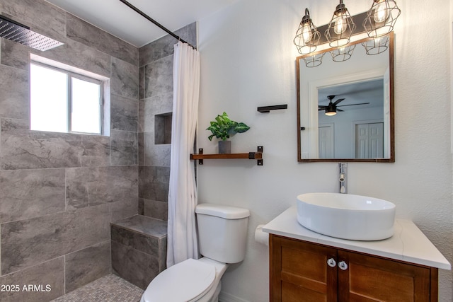 full bath featuring a tile shower, toilet, vanity, and a ceiling fan