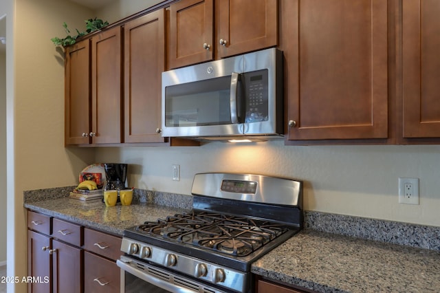 kitchen with appliances with stainless steel finishes and dark stone counters