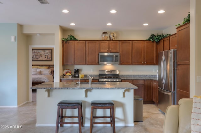 kitchen with sink, light tile patterned floors, a breakfast bar, stainless steel appliances, and a center island with sink