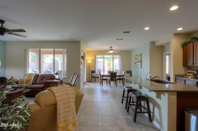 living room with sink, light tile patterned floors, and ceiling fan