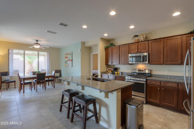 kitchen featuring stone countertops, sink, a kitchen breakfast bar, a kitchen island with sink, and stainless steel appliances