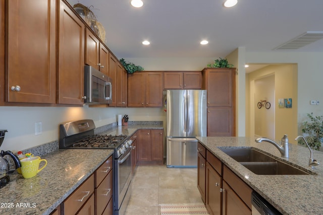 kitchen featuring light stone counters, stainless steel appliances, sink, and light tile patterned floors