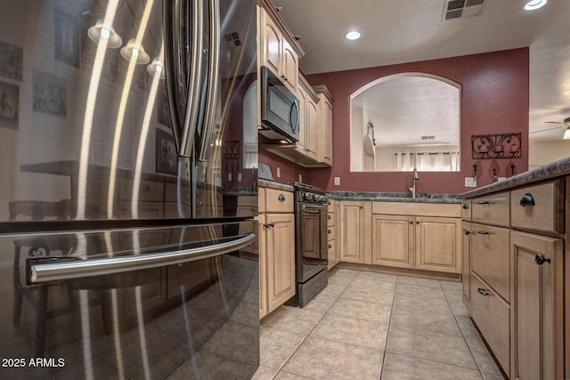 kitchen with fridge, sink, black range with gas cooktop, wall oven, and dark stone counters