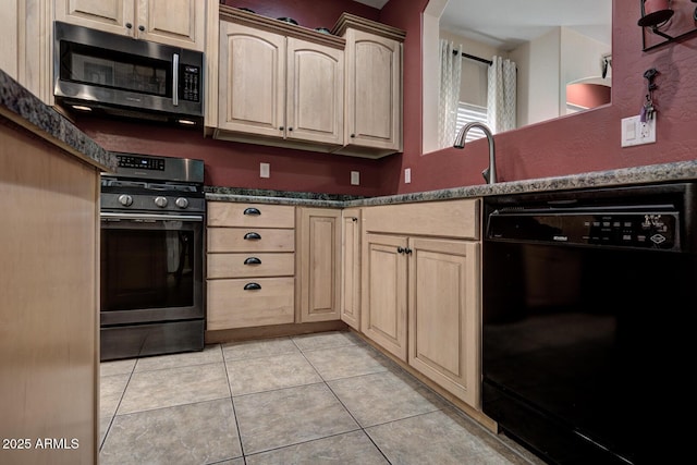 kitchen with light tile patterned floors, dark stone countertops, light brown cabinets, and stainless steel appliances