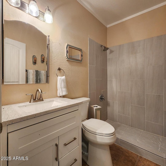 bathroom with tile patterned floors, tiled shower, vanity, and toilet