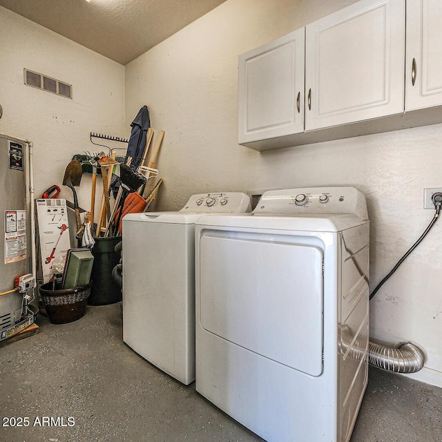 clothes washing area with cabinets, washing machine and dryer, and water heater