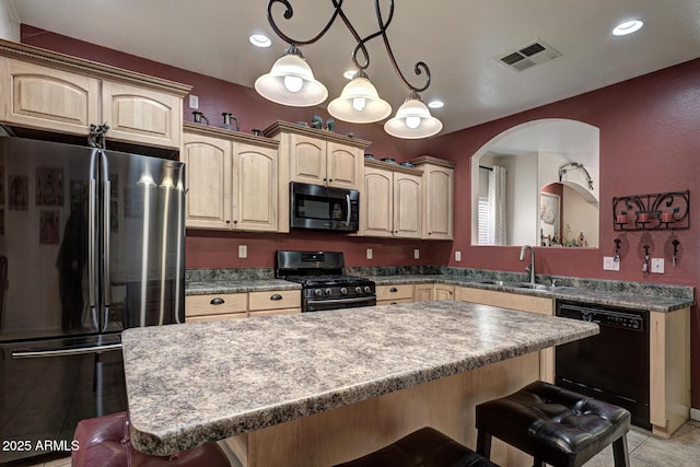 kitchen with a breakfast bar area, a center island, decorative light fixtures, black appliances, and sink