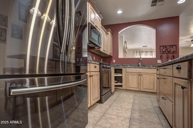 kitchen featuring light tile patterned floors, oven, refrigerator, black gas stove, and sink