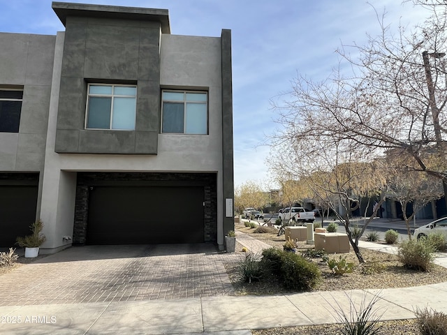 view of front facade with an attached garage, decorative driveway, and stucco siding