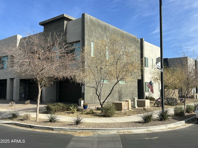 view of side of property with a garage, driveway, and stucco siding