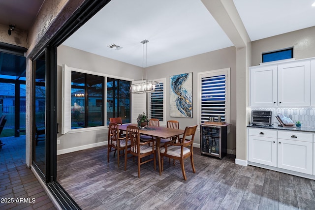 dining space featuring visible vents, baseboards, dark wood-type flooring, and a notable chandelier