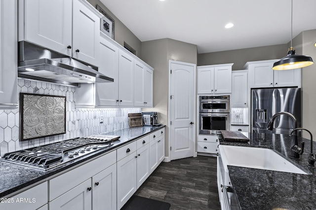 kitchen with a sink, stainless steel appliances, range hood, and white cabinetry