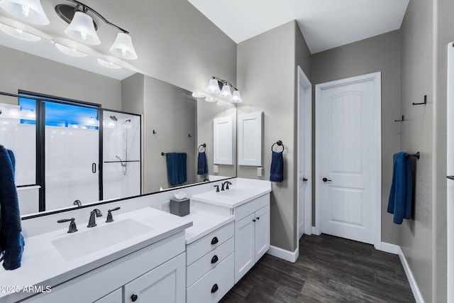 bathroom with a shower stall, wood finished floors, baseboards, and a sink