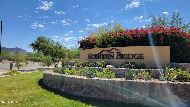 community / neighborhood sign with a lawn and a mountain view