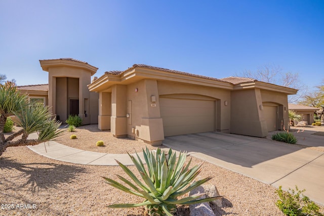 view of front of house featuring a tiled roof, a garage, driveway, and stucco siding