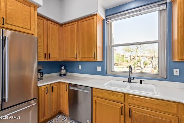 kitchen featuring brown cabinetry, stainless steel appliances, light countertops, and a sink