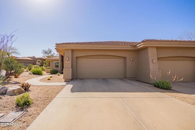 view of front facade featuring a tiled roof, stucco siding, an attached garage, and concrete driveway