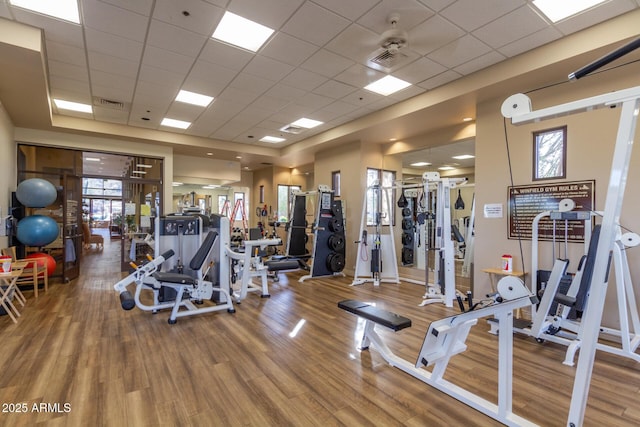 exercise room featuring wood finished floors, visible vents, and a paneled ceiling