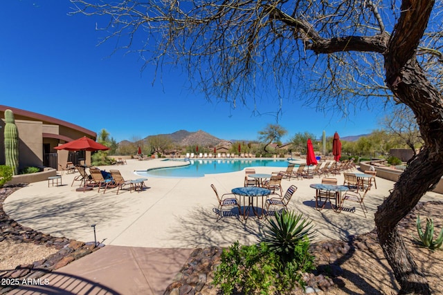 community pool featuring a patio area, a mountain view, and fence