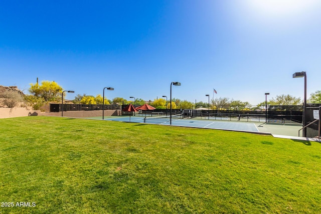 view of property's community featuring a yard, a tennis court, and fence