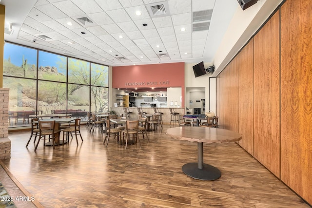 dining room featuring visible vents, a wall of windows, and wood finished floors