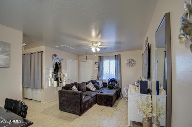 living area featuring light tile patterned flooring, a ceiling fan, visible vents, and a textured ceiling