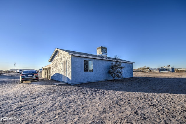 view of side of property with cooling unit and stucco siding