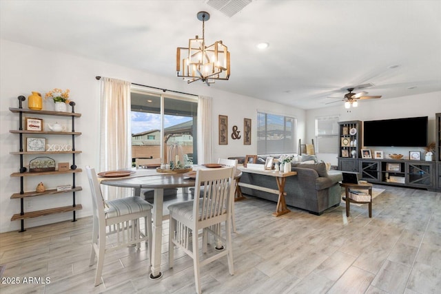 dining space featuring ceiling fan with notable chandelier, visible vents, and light wood finished floors