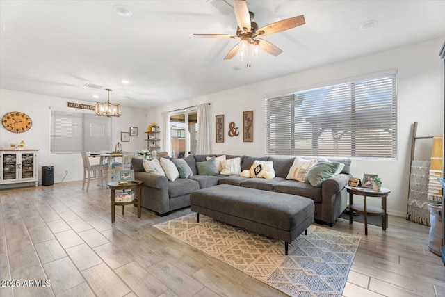 living area featuring recessed lighting, baseboards, light wood-style floors, and ceiling fan with notable chandelier