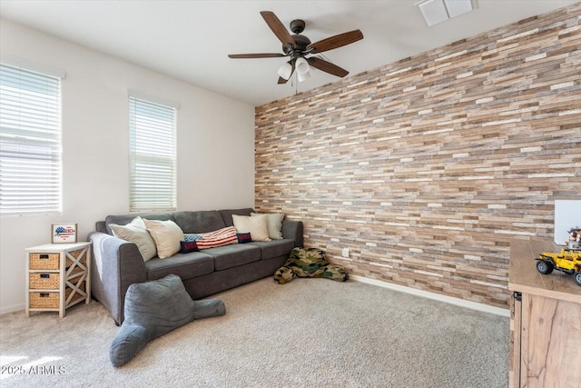 living area featuring visible vents, baseboards, ceiling fan, and carpet flooring