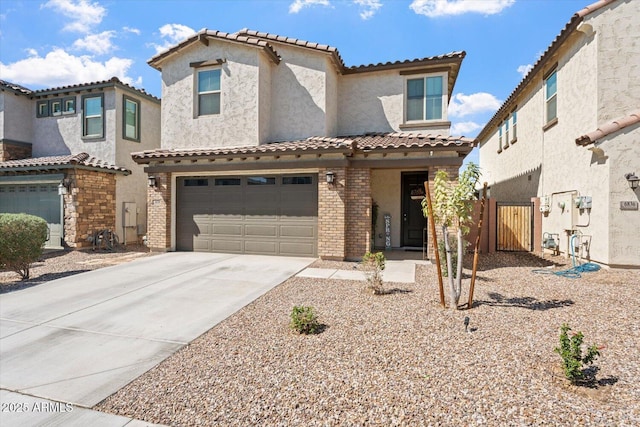 mediterranean / spanish house featuring an attached garage, stucco siding, concrete driveway, a tile roof, and brick siding