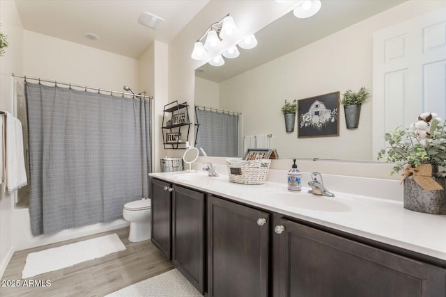 full bath featuring a sink, toilet, wood finished floors, and double vanity