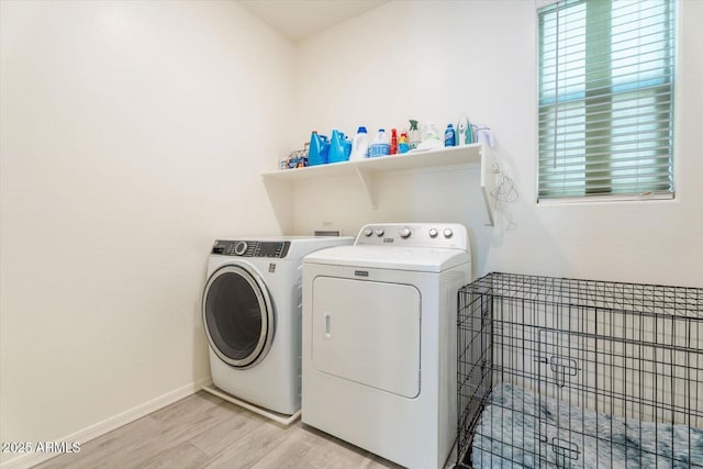 laundry area with laundry area, washer and dryer, baseboards, and light wood-style floors