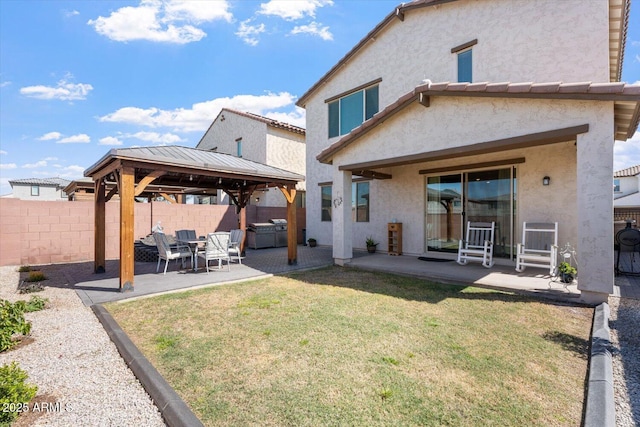 back of property with stucco siding, a lawn, fence, a gazebo, and a patio area