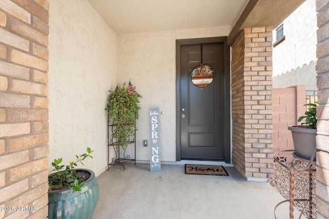 entrance to property with stucco siding and brick siding