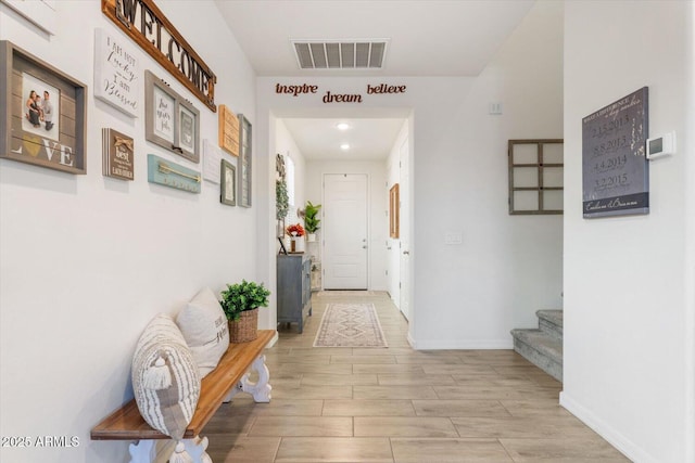 corridor with visible vents, light wood-style flooring, stairway, and baseboards