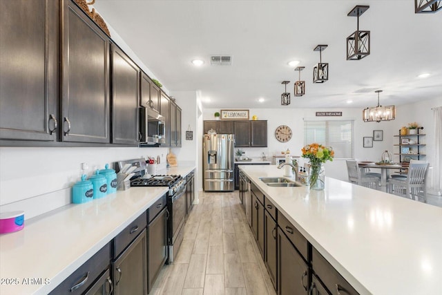 kitchen with a sink, hanging light fixtures, light countertops, stainless steel appliances, and dark brown cabinets