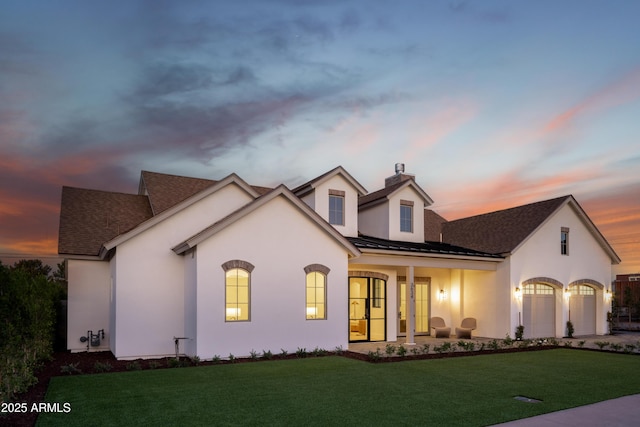 view of front facade featuring metal roof, french doors, stucco siding, a front lawn, and a standing seam roof