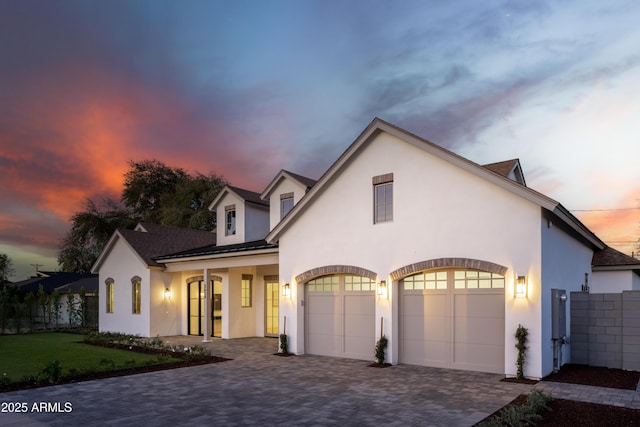 view of front of house featuring a garage, a front lawn, decorative driveway, and stucco siding