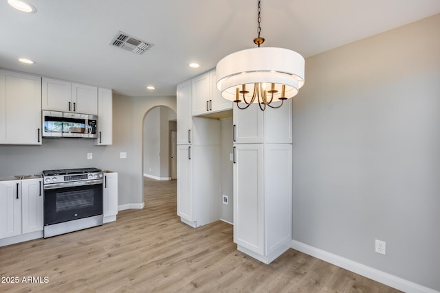 kitchen with light wood finished floors, visible vents, appliances with stainless steel finishes, white cabinets, and baseboards
