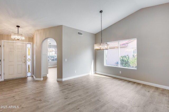 entrance foyer featuring a chandelier, arched walkways, lofted ceiling, visible vents, and light wood-type flooring