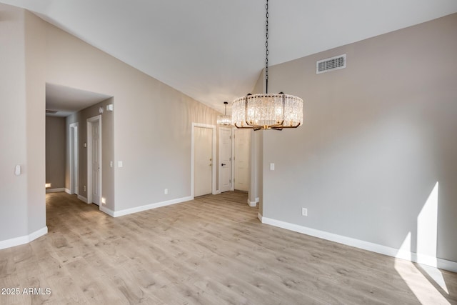 unfurnished dining area with baseboards, visible vents, a chandelier, light wood-type flooring, and high vaulted ceiling