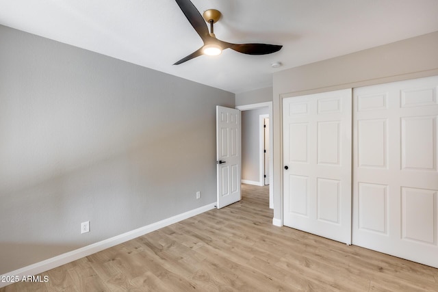 unfurnished bedroom featuring light wood-style floors, a ceiling fan, baseboards, and a closet