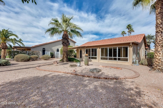 rear view of property featuring a sunroom, fence, a patio, and stucco siding